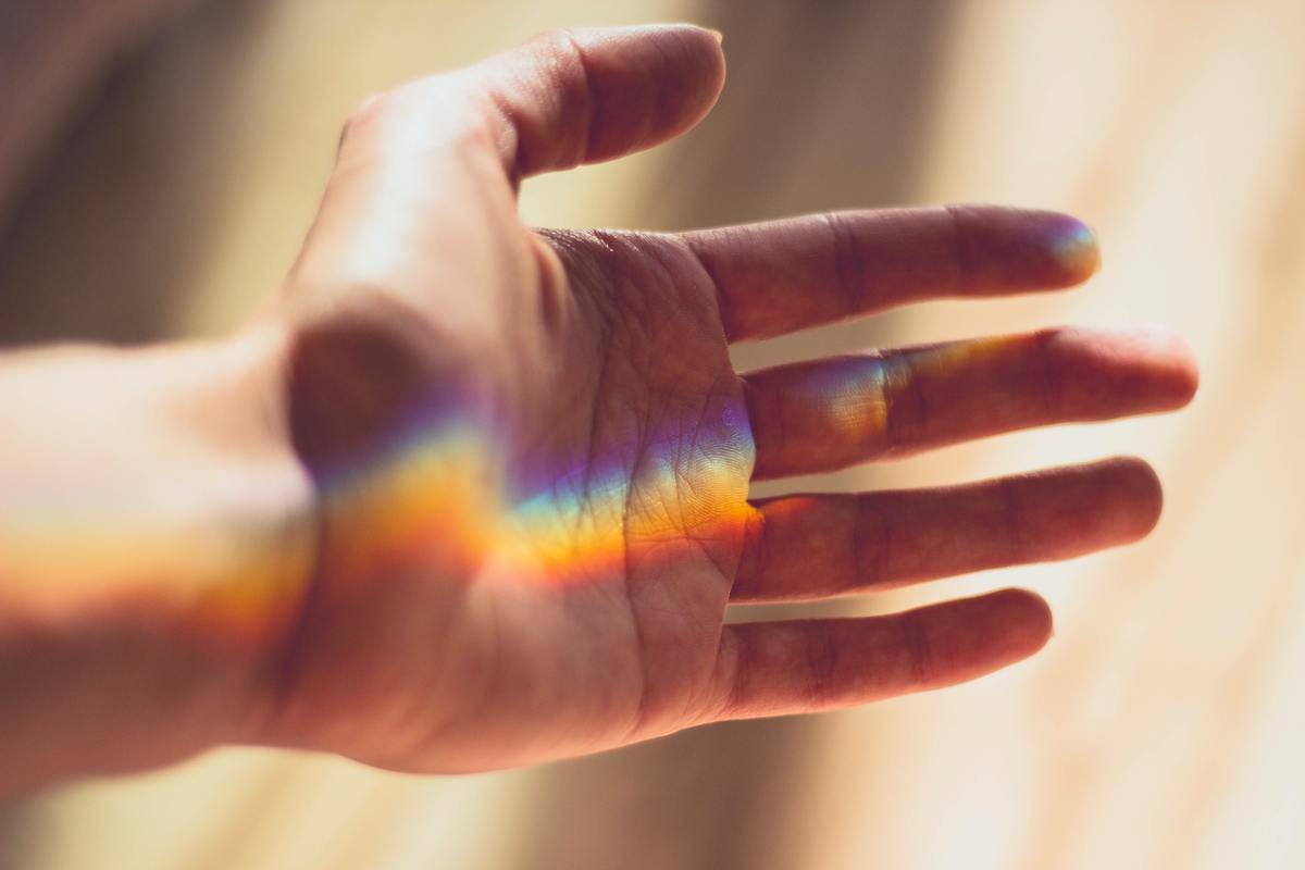 Someone's palm with a strip of rainbow lighting across it.