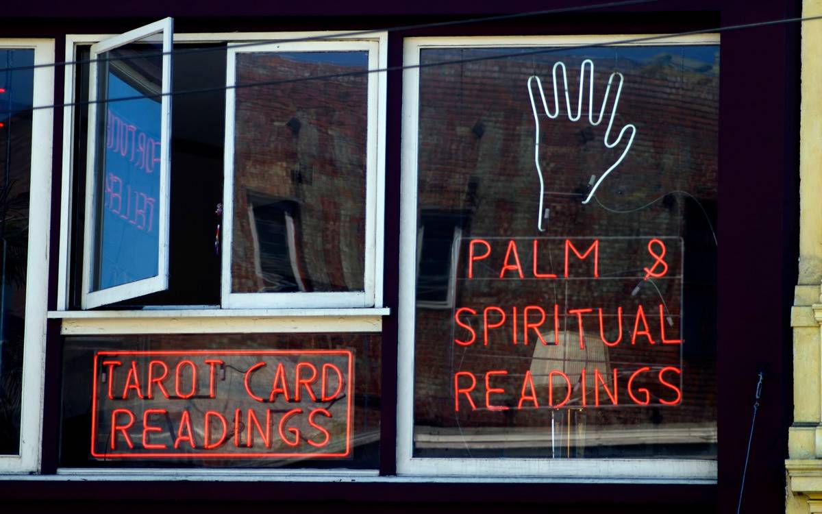 A neon sign in a window advertising palm readings.