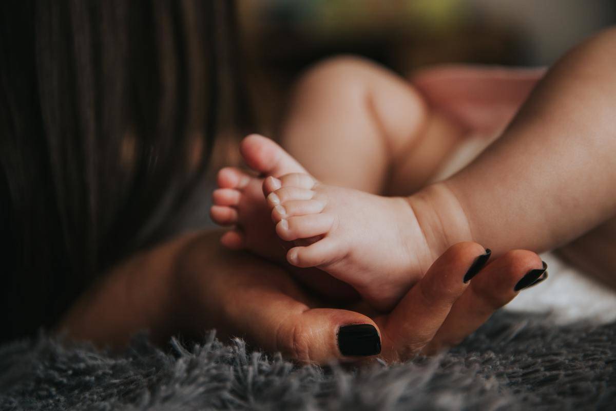 A mother cradling her baby's feet in her hand.