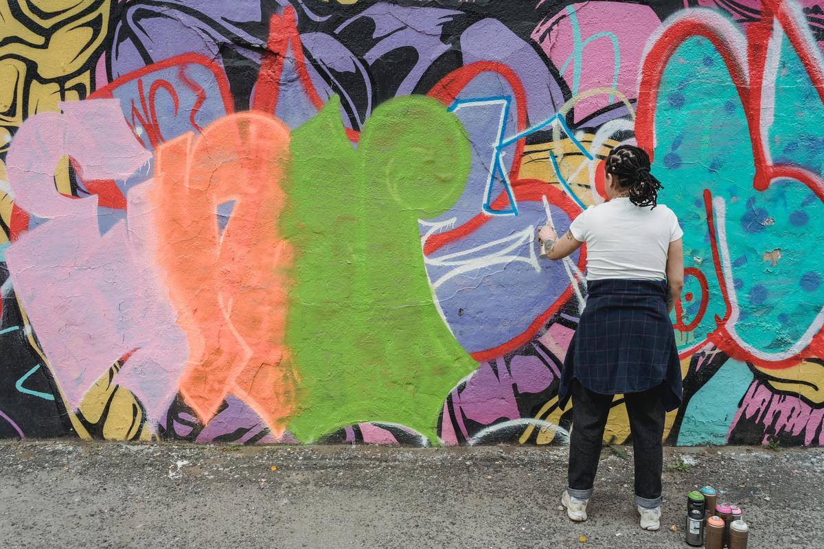 A woman spray painting graffiti on a wall.