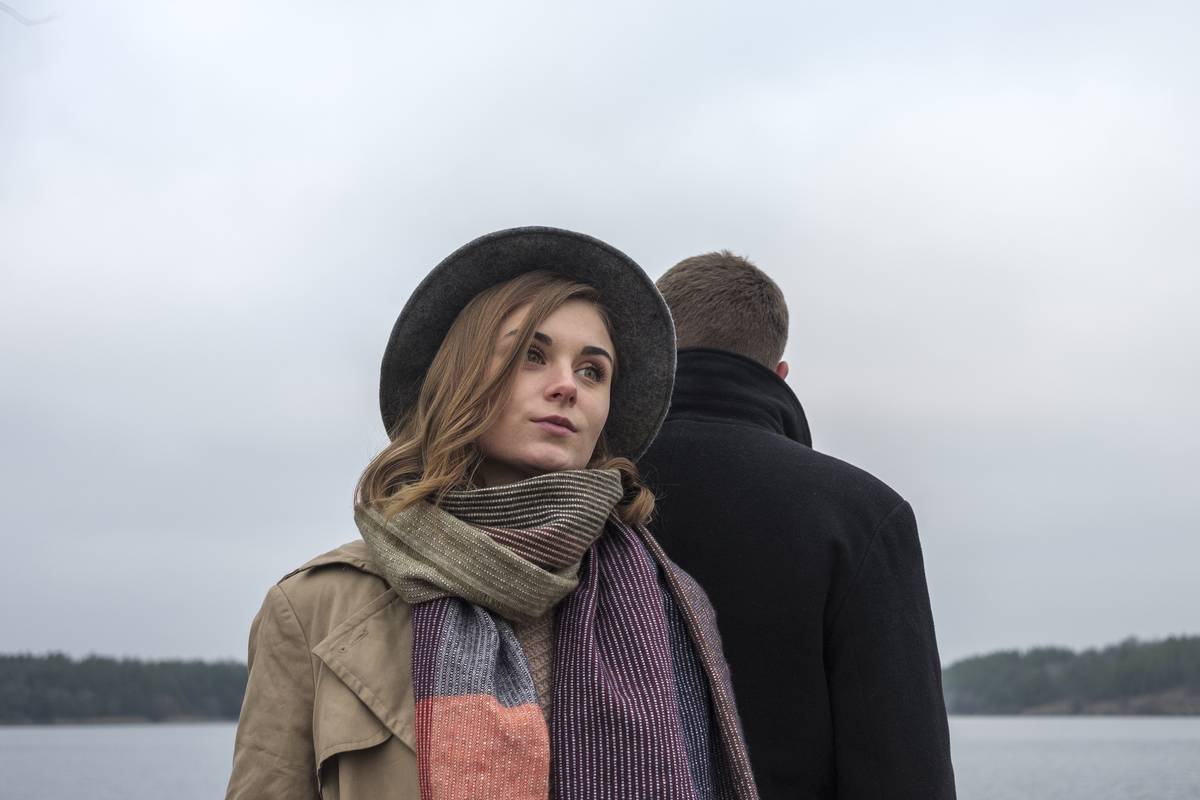 Young couple ignoring one another after a fight or argument standing back to back in a low angle view outdoors in winter with focus to the woman