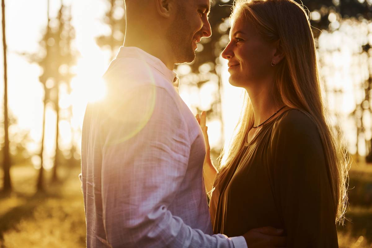 Cheerful couple is outdoors in the forest at daytime.