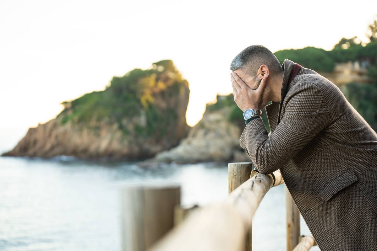 Portrait of a sad man next to the sea with mountains on the background