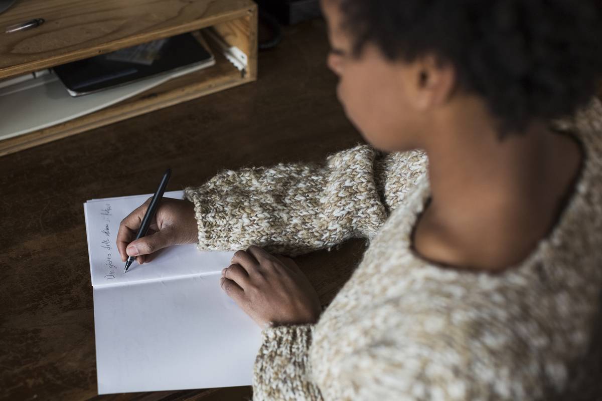 Young woman at desk writing in notebook