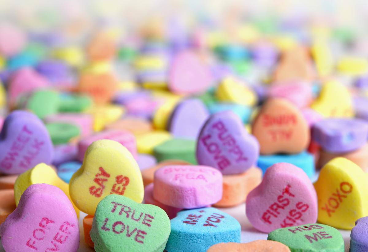 A photo filled with Valentine's Day candy hearts, the ones up front in focus so they can be read.