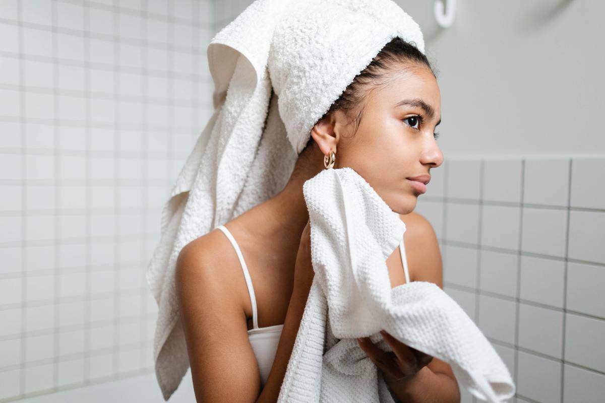 A woman wiping her face dry with a towel.