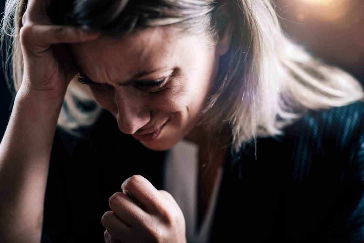 A woman clutching her own head while crying.