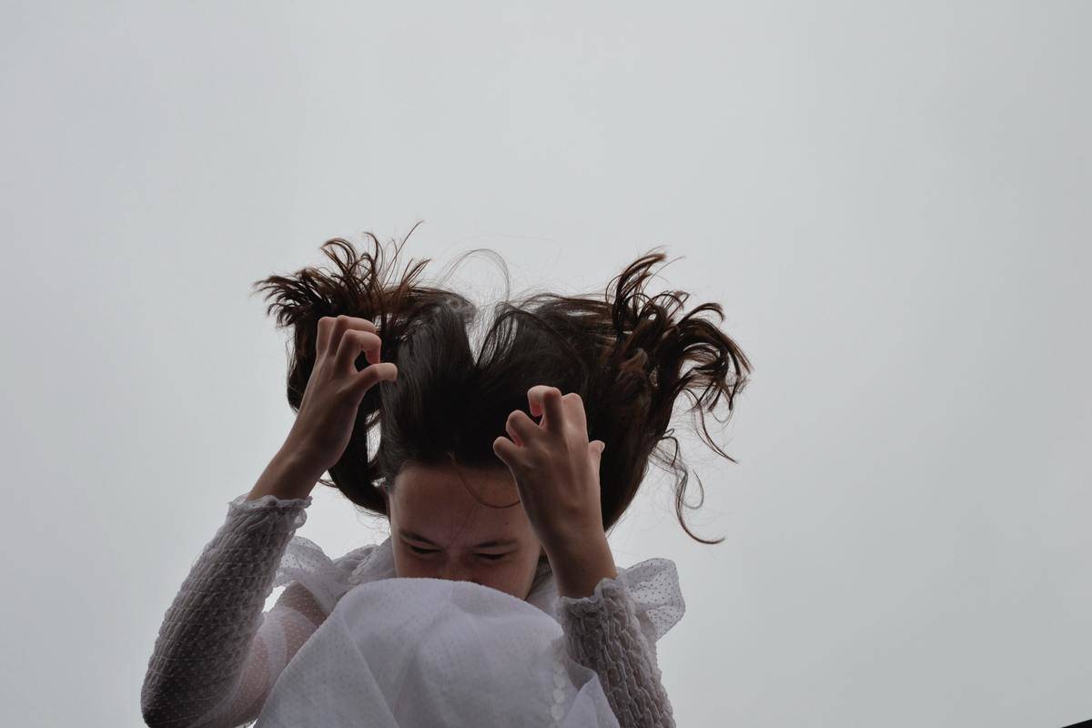 A woman throwing her head forward towards clutched hands.