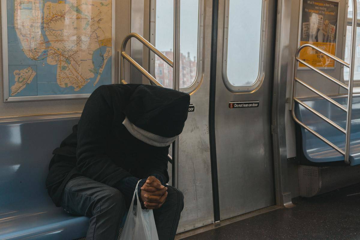 Someone sitting hunched over in a subway car.