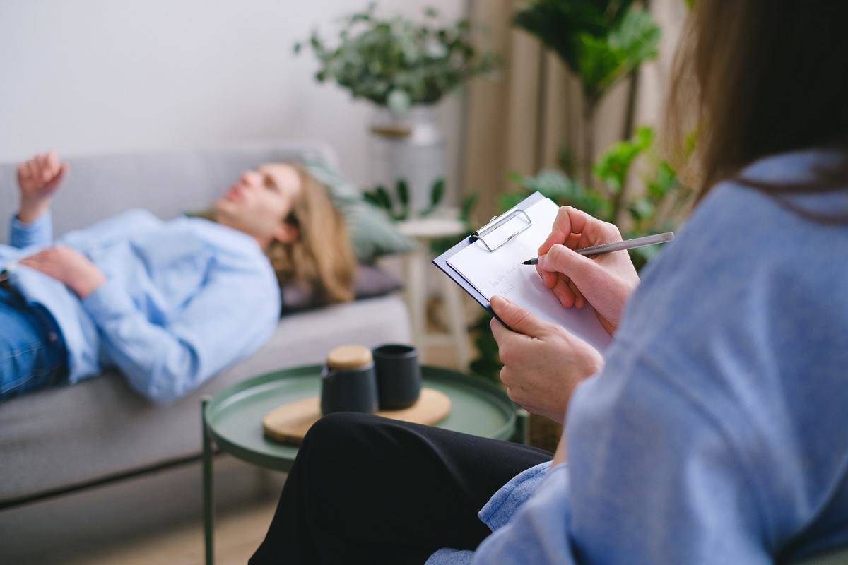 Someone laying on a couch, speaking as a therapist takes notes.