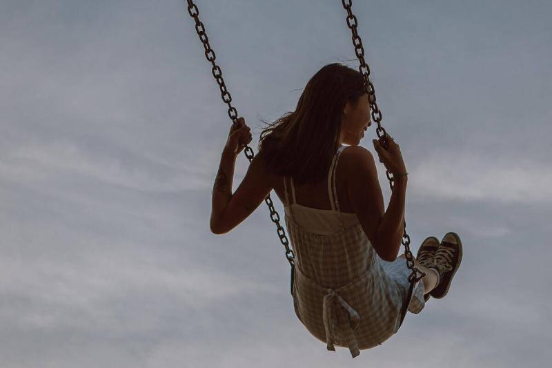 A woman on a swing before an expansive sky.