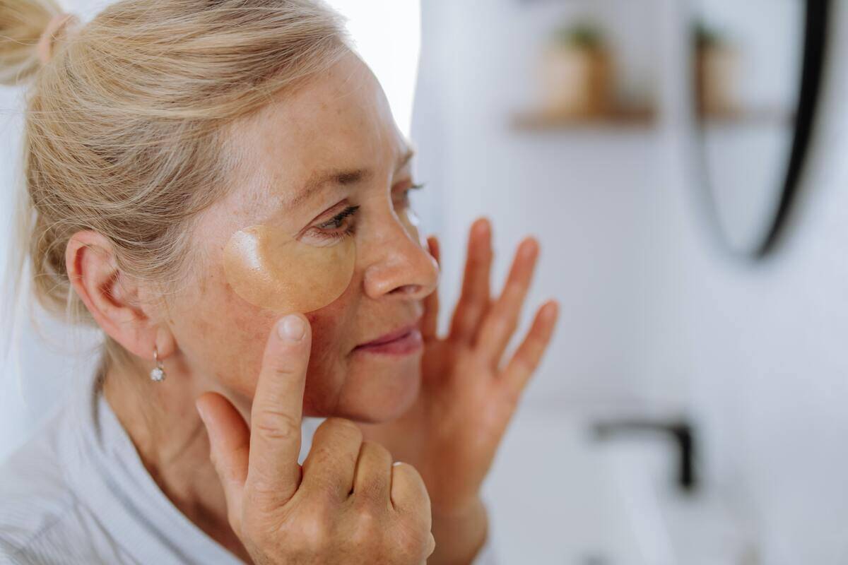 A woman putting on a face-cleansing patch.