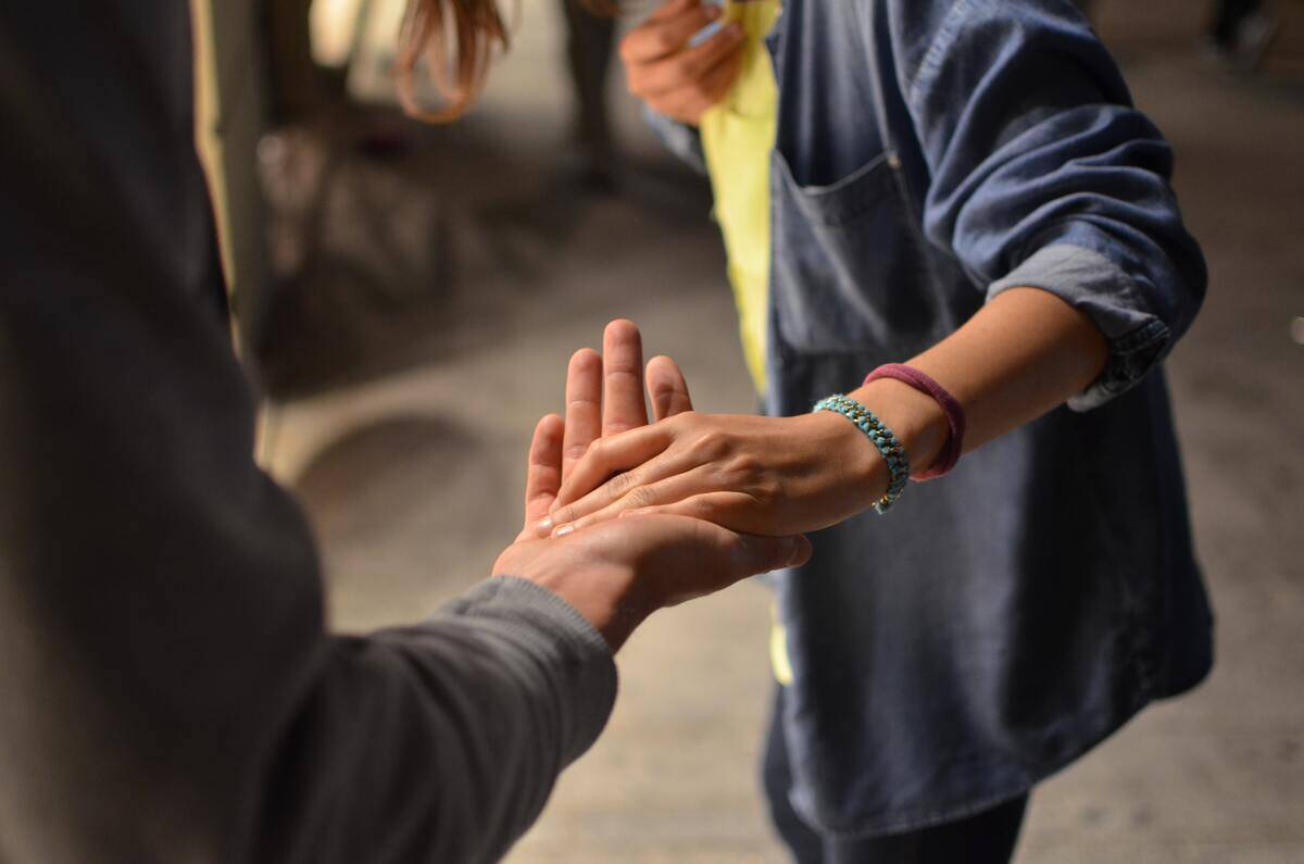 Someone reaching out to take another person's hand in guidance.