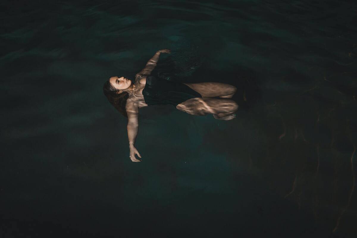 A woman floating in dark water.