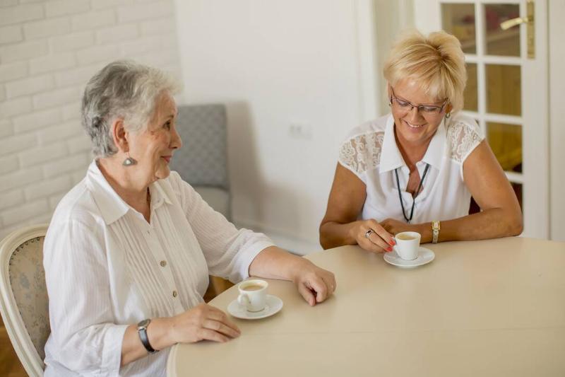 Two older women drinking coffee at home and talking