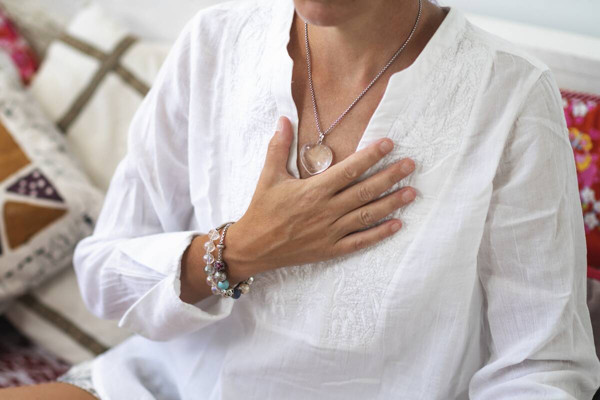 A woman sitting with her hand over the center of her chest.