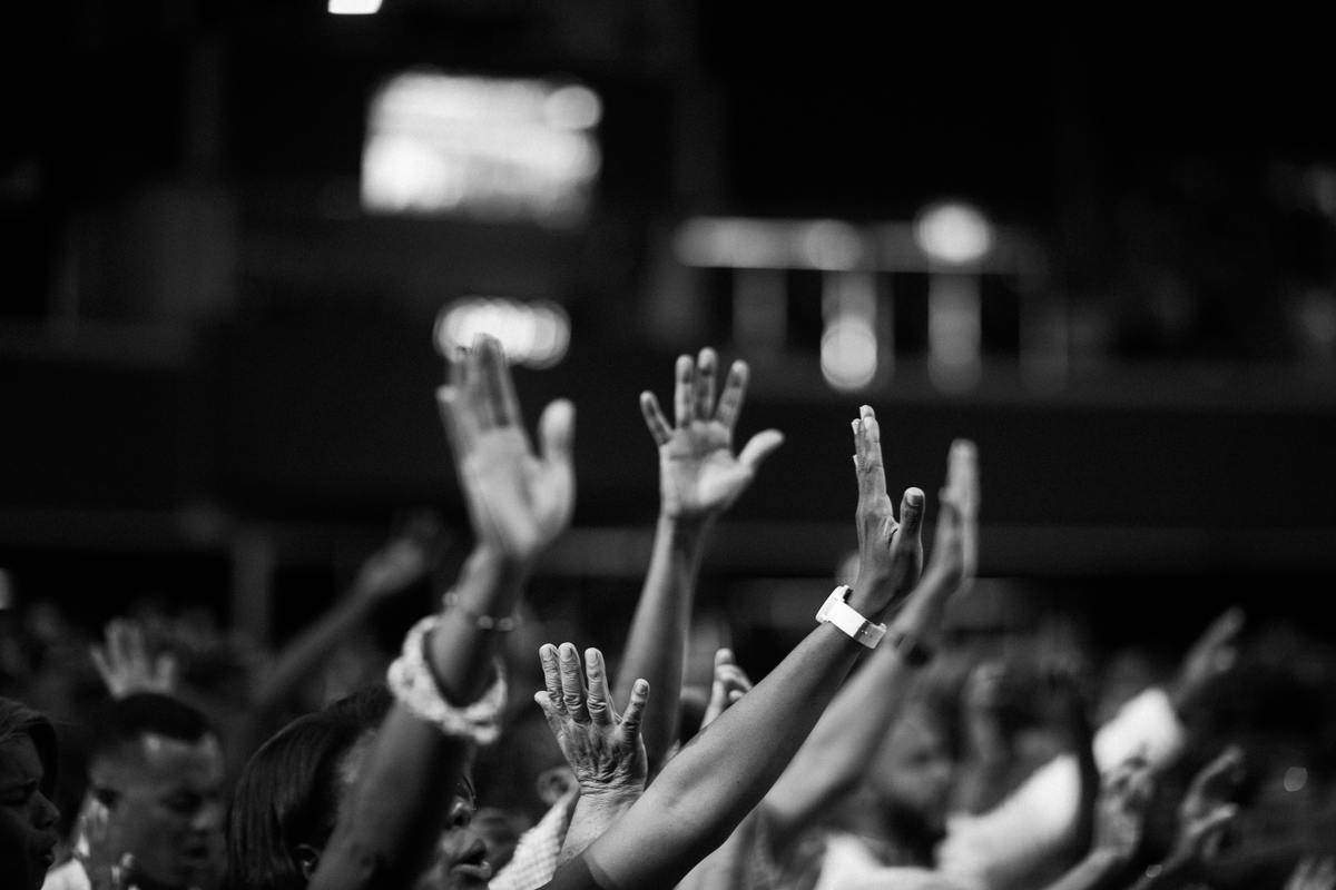 A greyscale image of hands in a crowd reaching upwards.