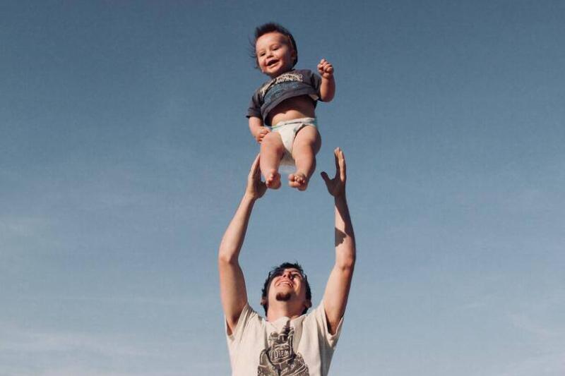 A father throwing his baby up in the air.