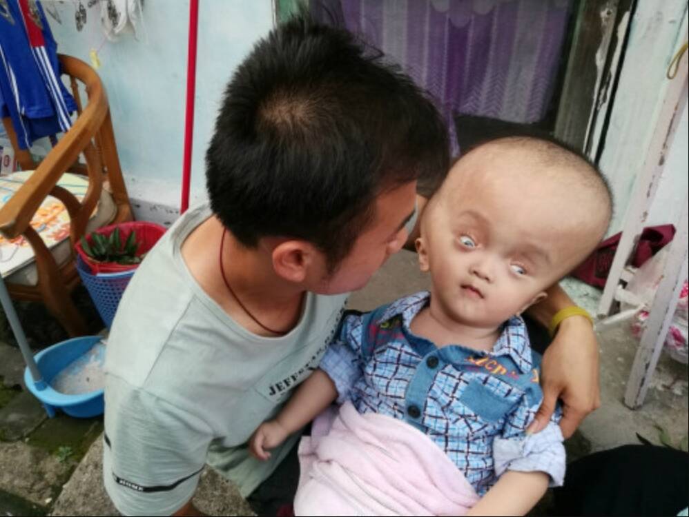 Jiang Laicai holding one of his twin boys in his arms.