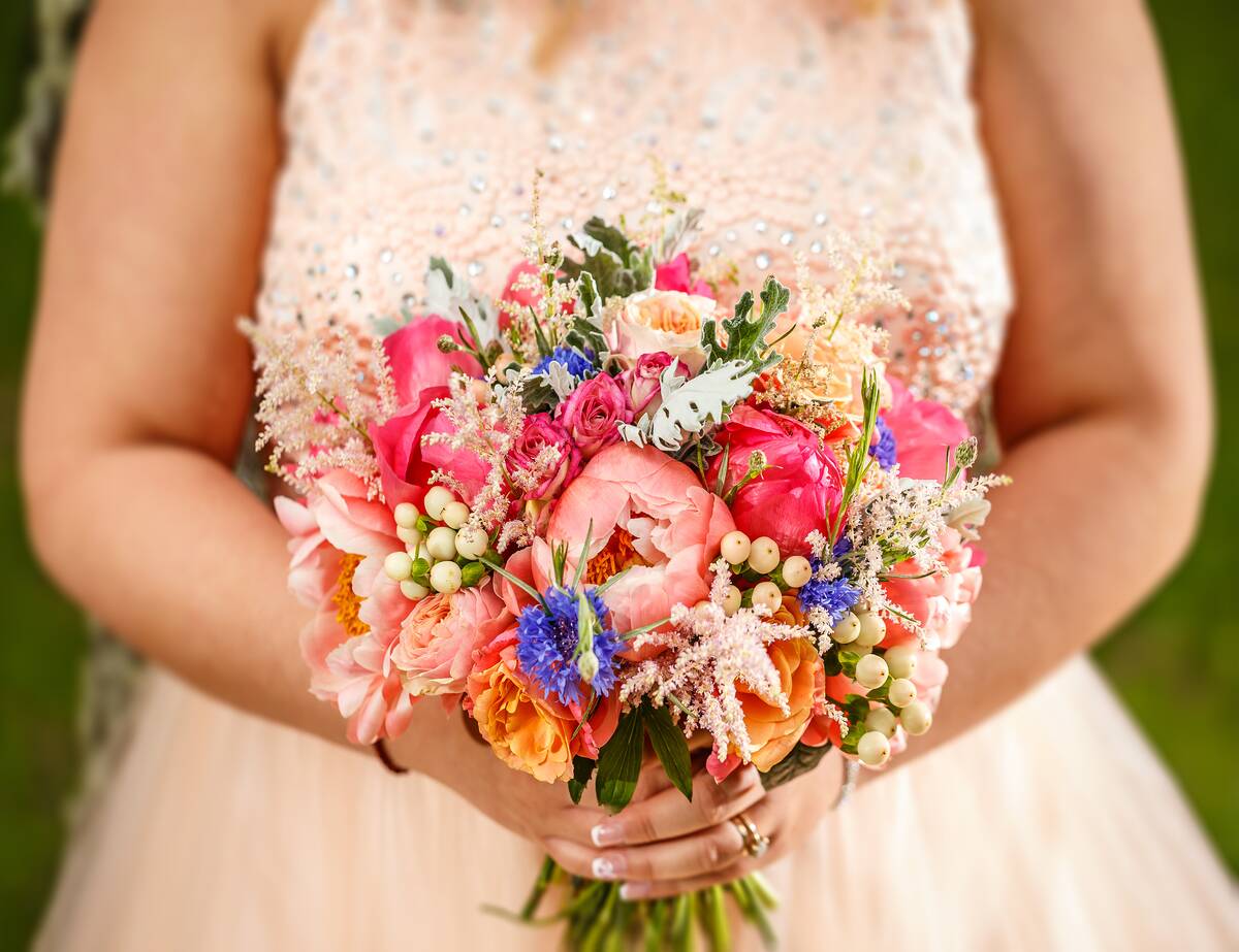 A very colorful wedding bouquet being held by a bride.