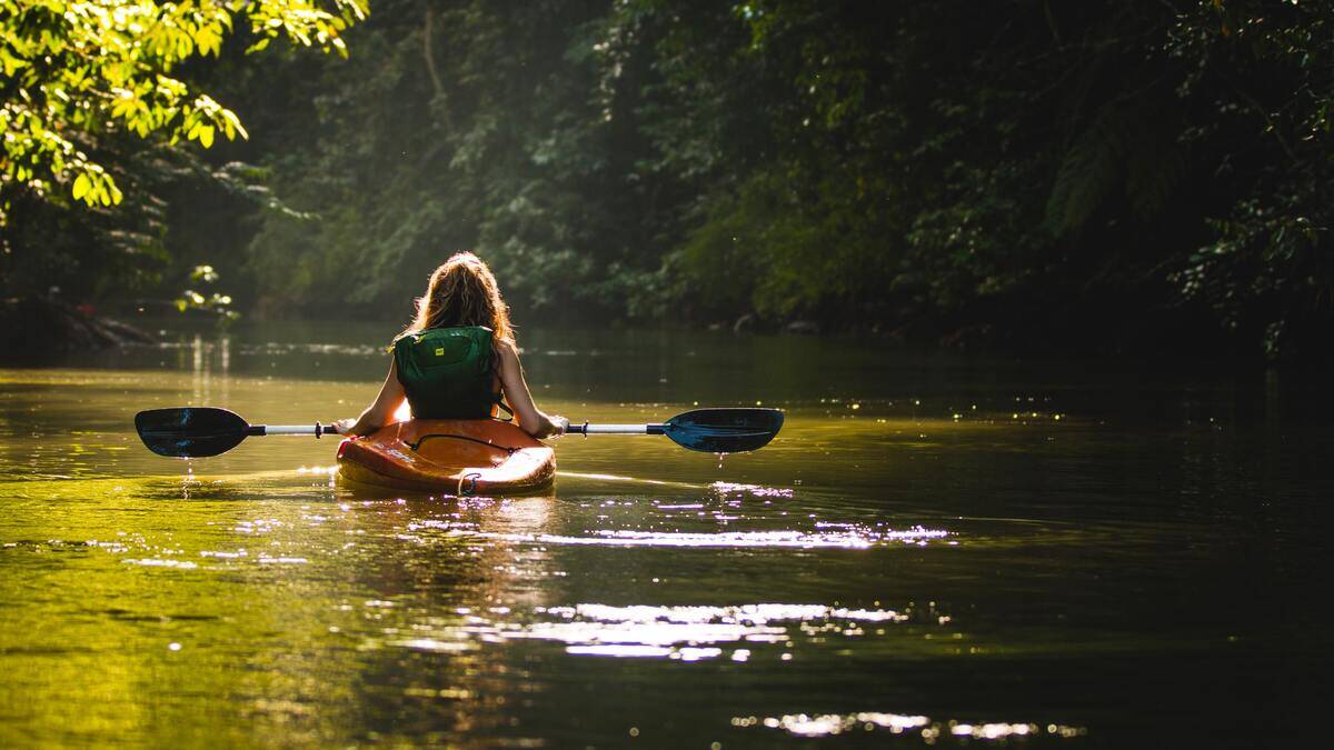 A woman in a kayak, kayaking down a river.