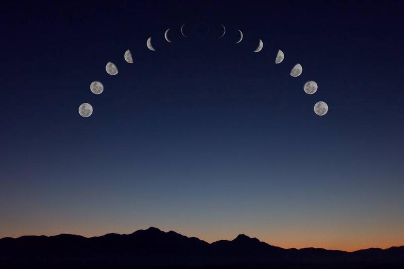 A sky above a mountain range showing all the phases of the moon.
