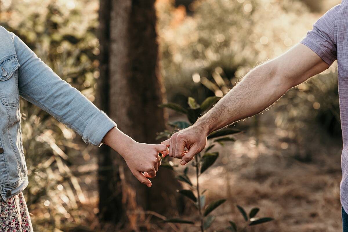 Two people linking pinky fingers.