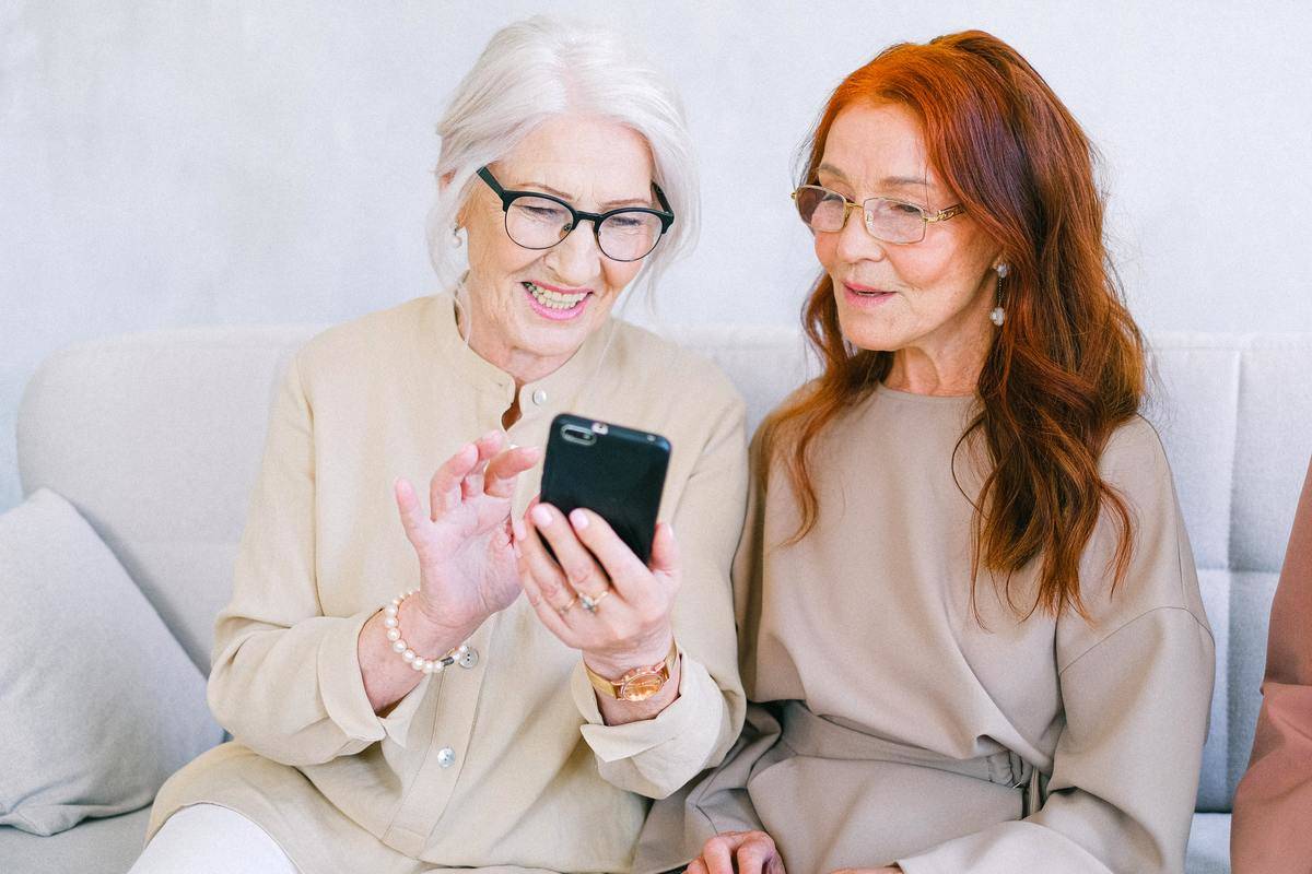 Two women gossiping as they look at one of the woman's phones.