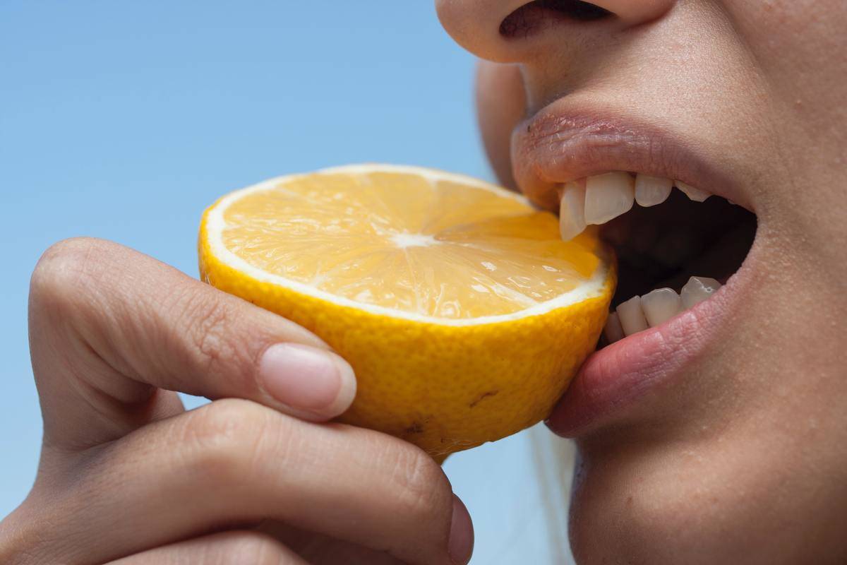 Someone biting into a lemon that's been sliced in half.