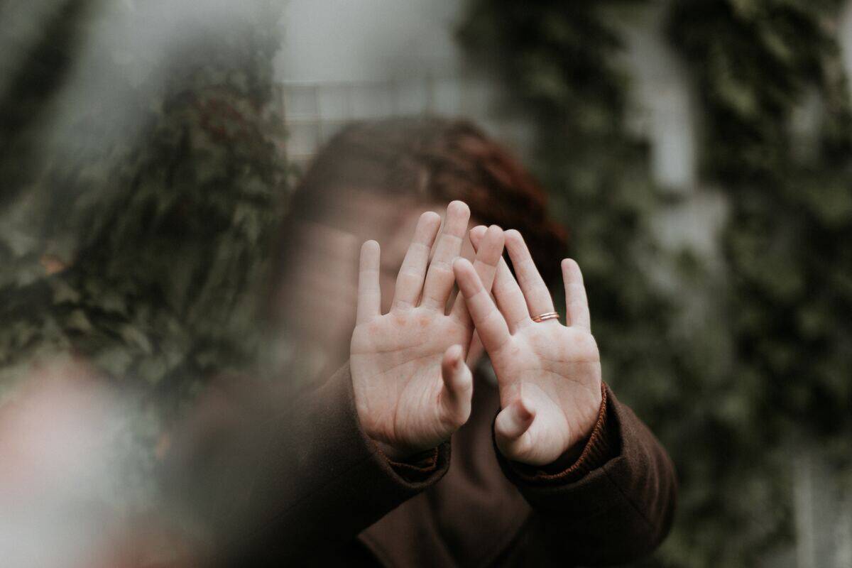 A slightly blurry image of a woman covering her face with her hands.