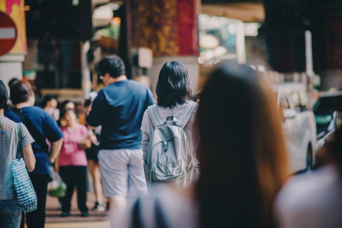 A street crowd walking away, the focus on one woman in the center.