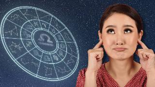 A woman plugging her ears with her fingers against a starry background, next to an astrological wheel.