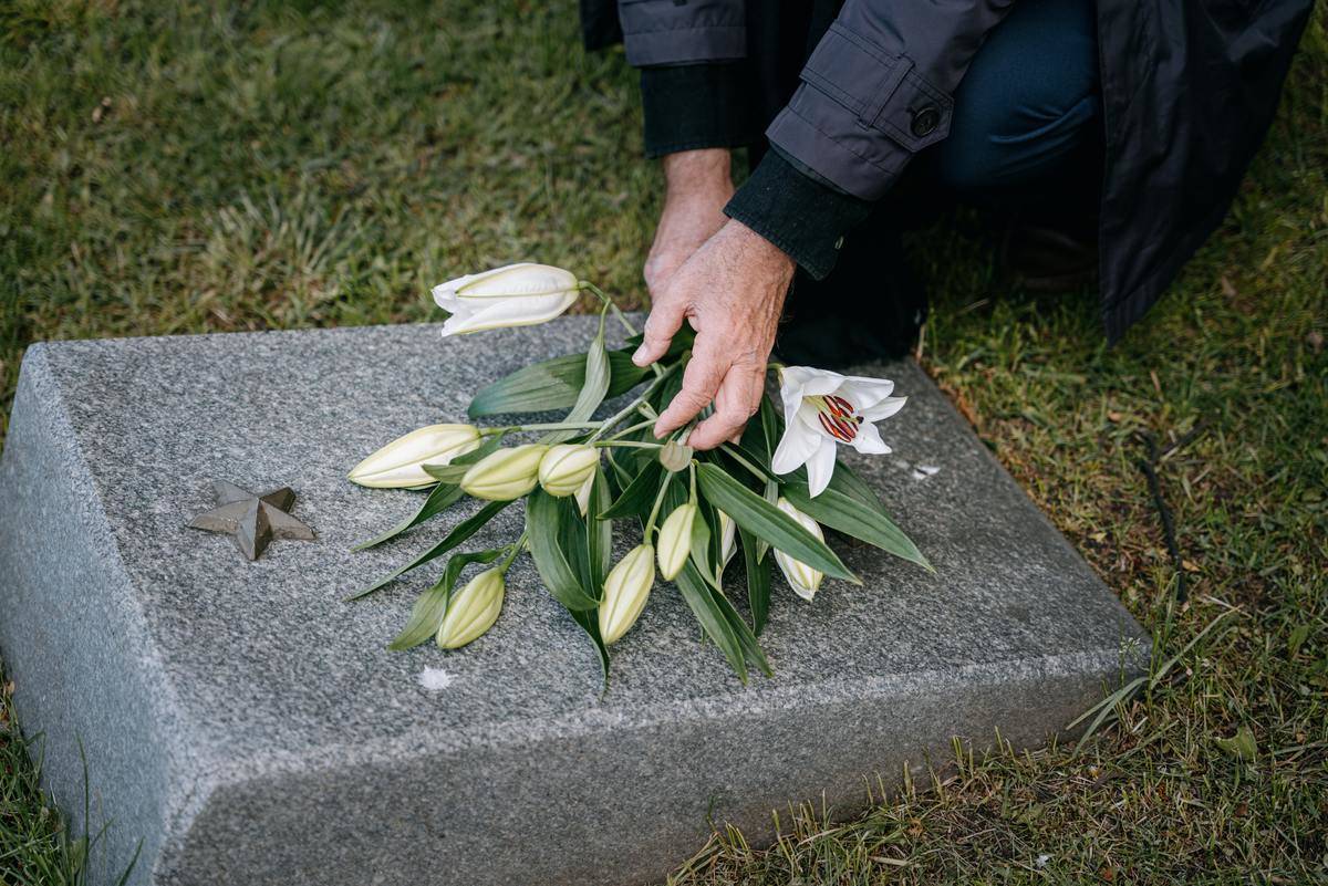 Someone laying flowers down on a grave.