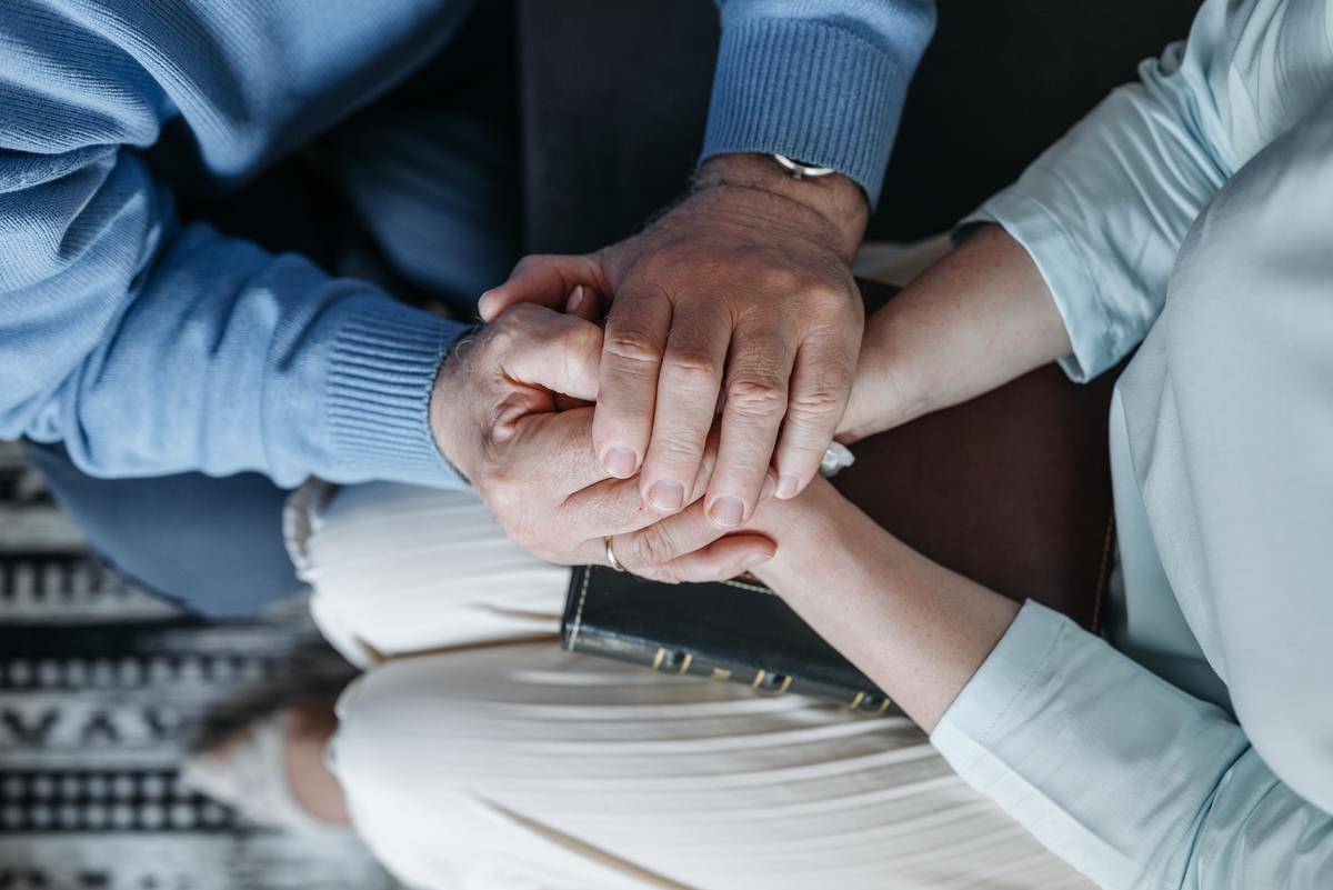 Two people holding hands in comfort.