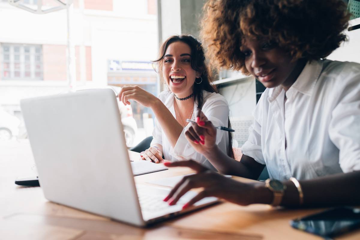 two multiracial young women studying and having fun in a coworking studio