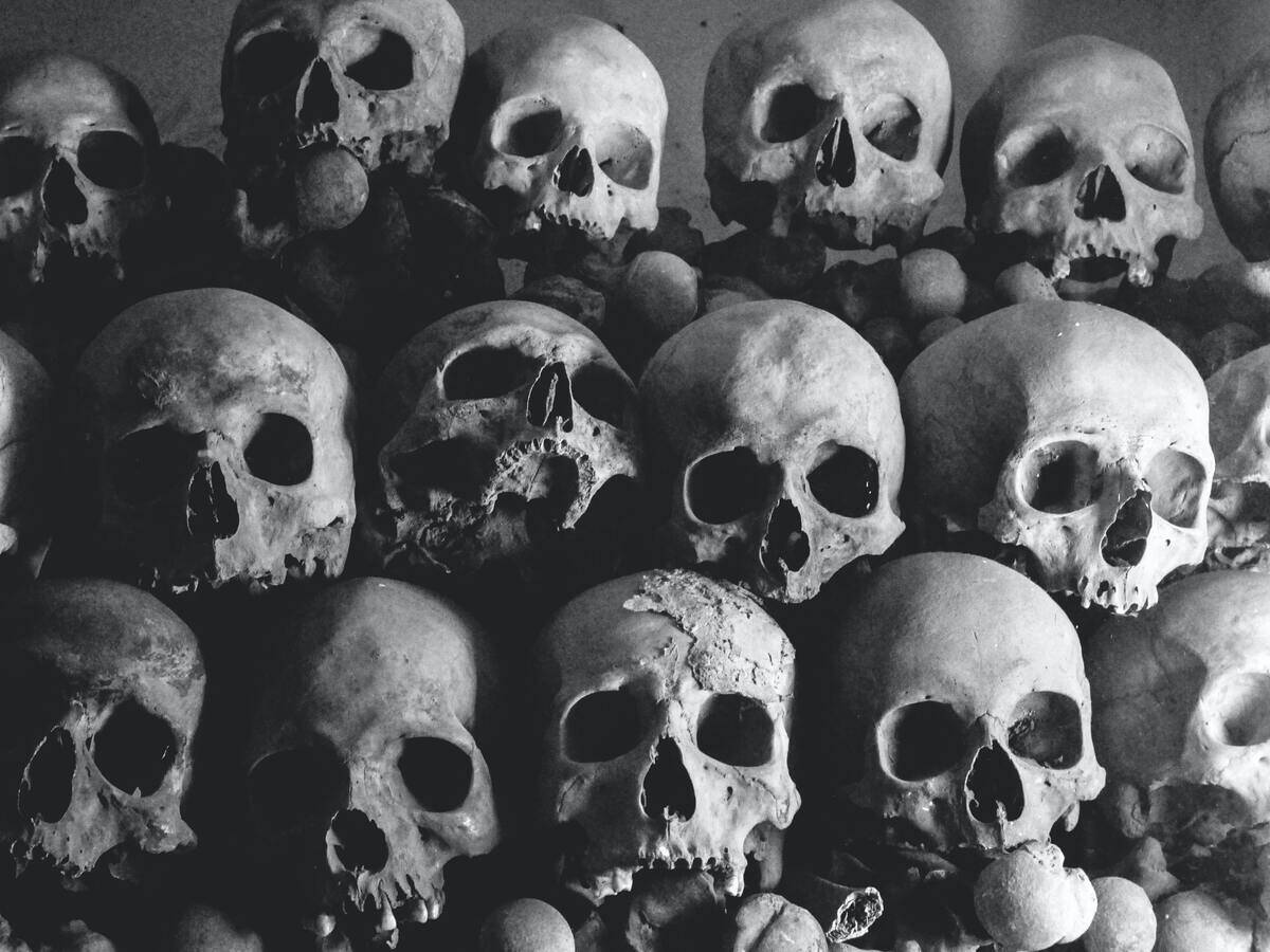 A greyscale image of rows of skulls atop one another.