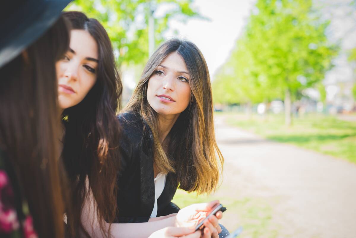 Three young female friends having conversation in park