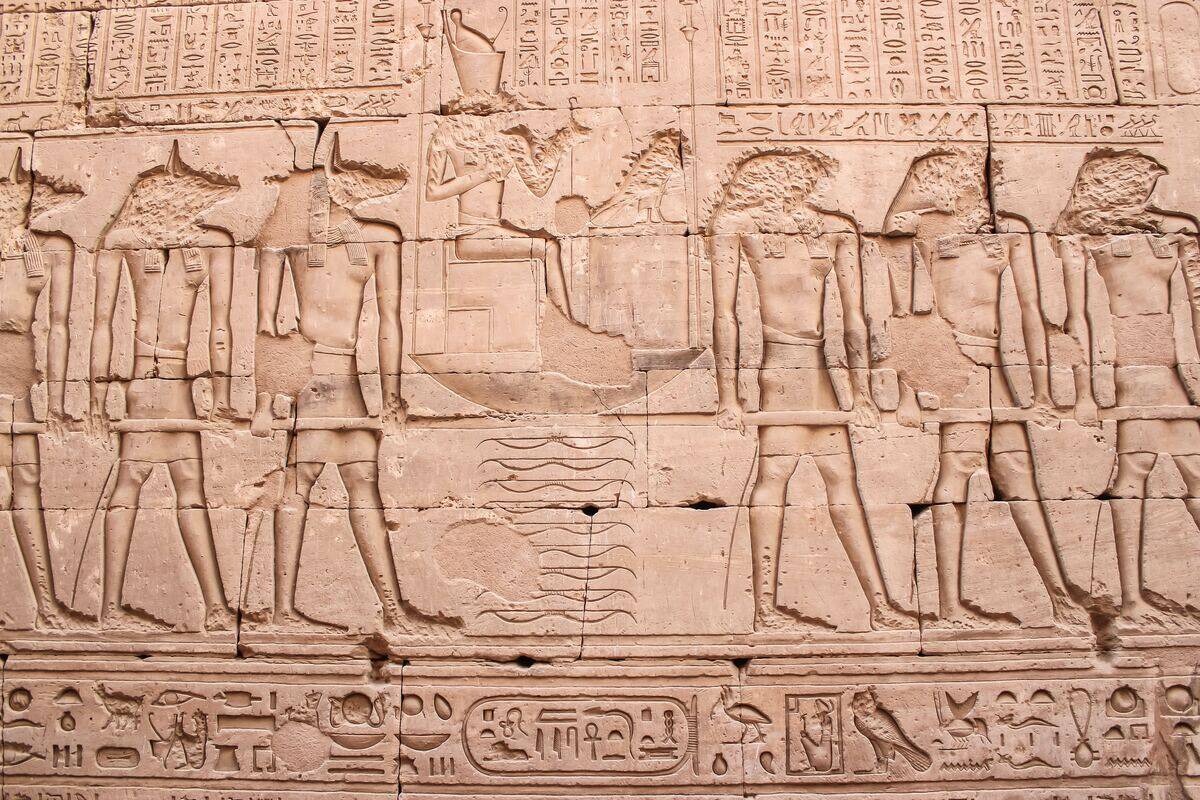 Ancient Egyptian wall carvings depicting people, gods, and various hieroglyphs. 