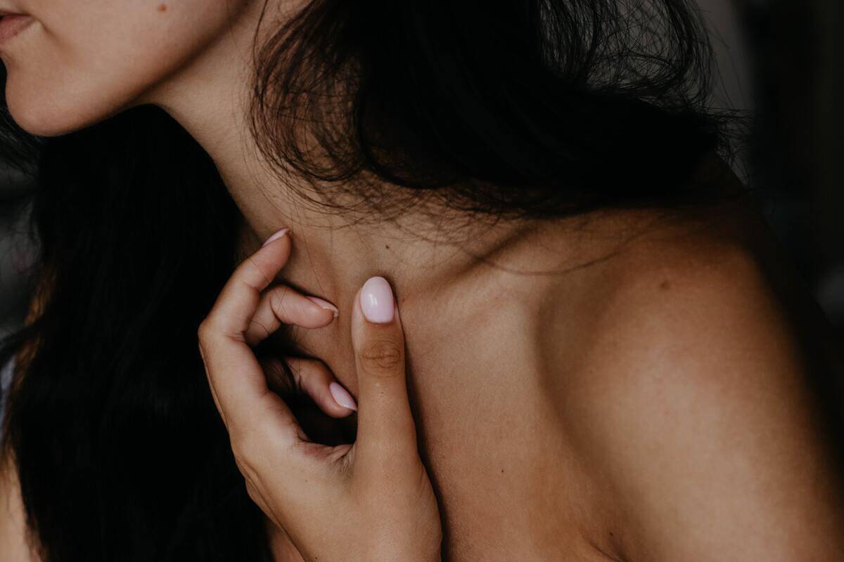 A closeup of someone's hand upon their collarbone, also showing their jaw and shoulder.