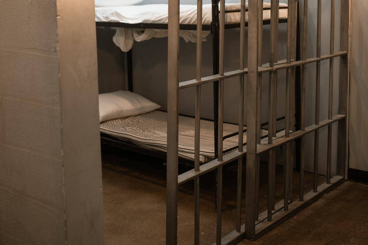 bed in a prison cell with a slightly open door.