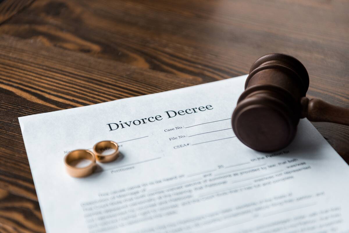 divorce decree, wedding rings and judge hammer on wooden table