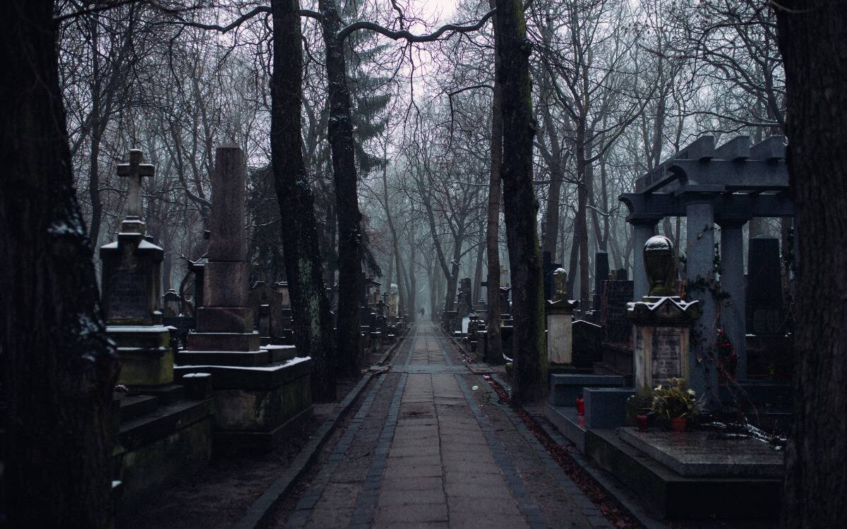 A stone pathway in a cemetery on a dark, gloomy day.