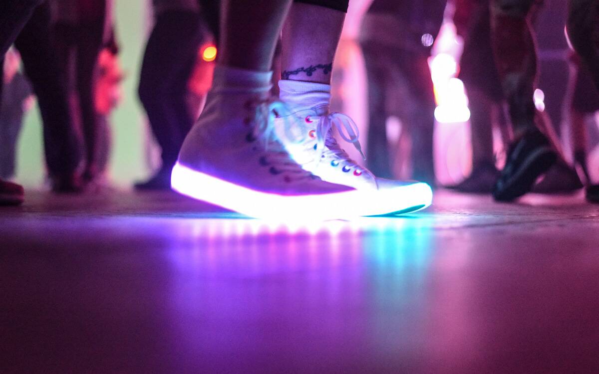 Someone wearing a pair of shoes with lightup soles on a dance floor.
