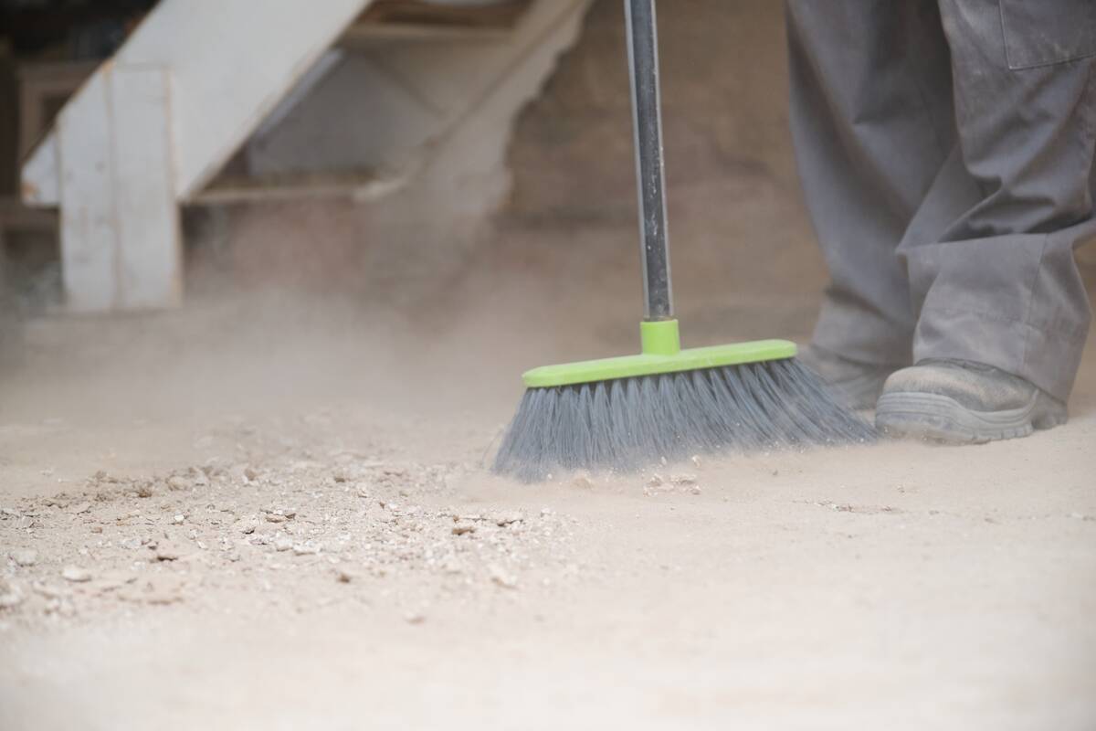 Close up of a young caucasian construction worker sweeping the floor at a construction site.
