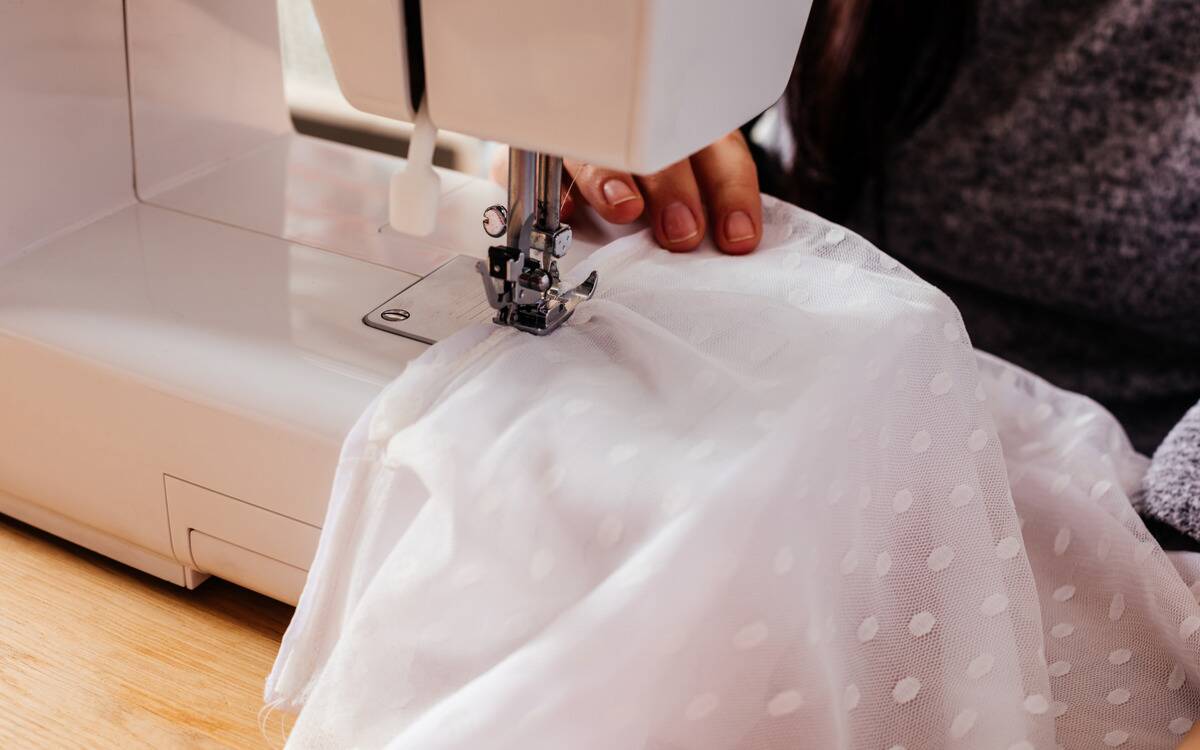 Someone fixing a wedding dress on a sewing machine.