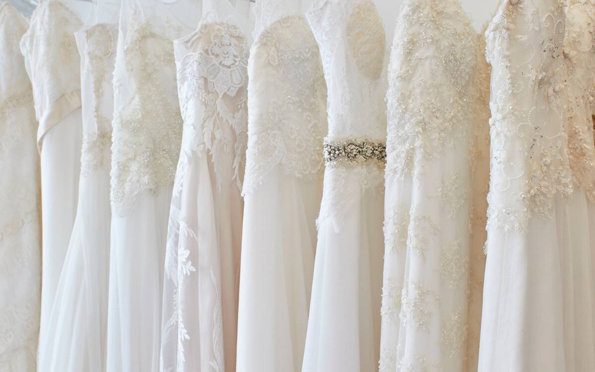 A selection of wedding dresses all lined up on a clothing rack.