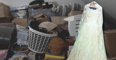 Trash and boxes stacked up against a wall with an image of a vintage wedding dress atop it.