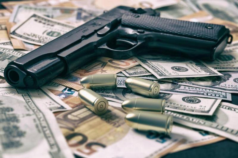Pistol and bullets on dollar and euro banknotes background