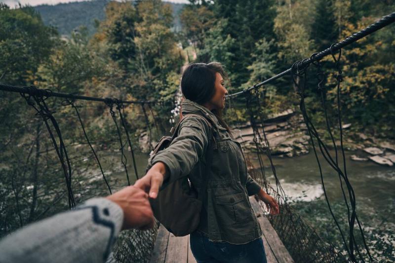 Woman holding hands with her boyfriend while walking on the suspension bridge