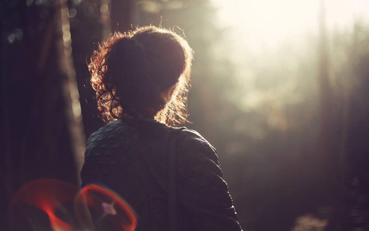 A woman walking outside, facing the sun, creating a peaceful scene.